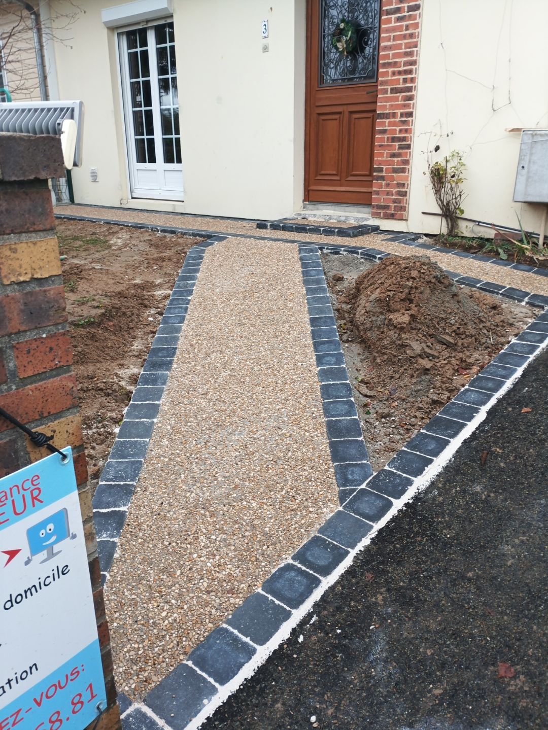 Chemin d acces en gravier stabilise avec bordure en paves noirs devant une maison