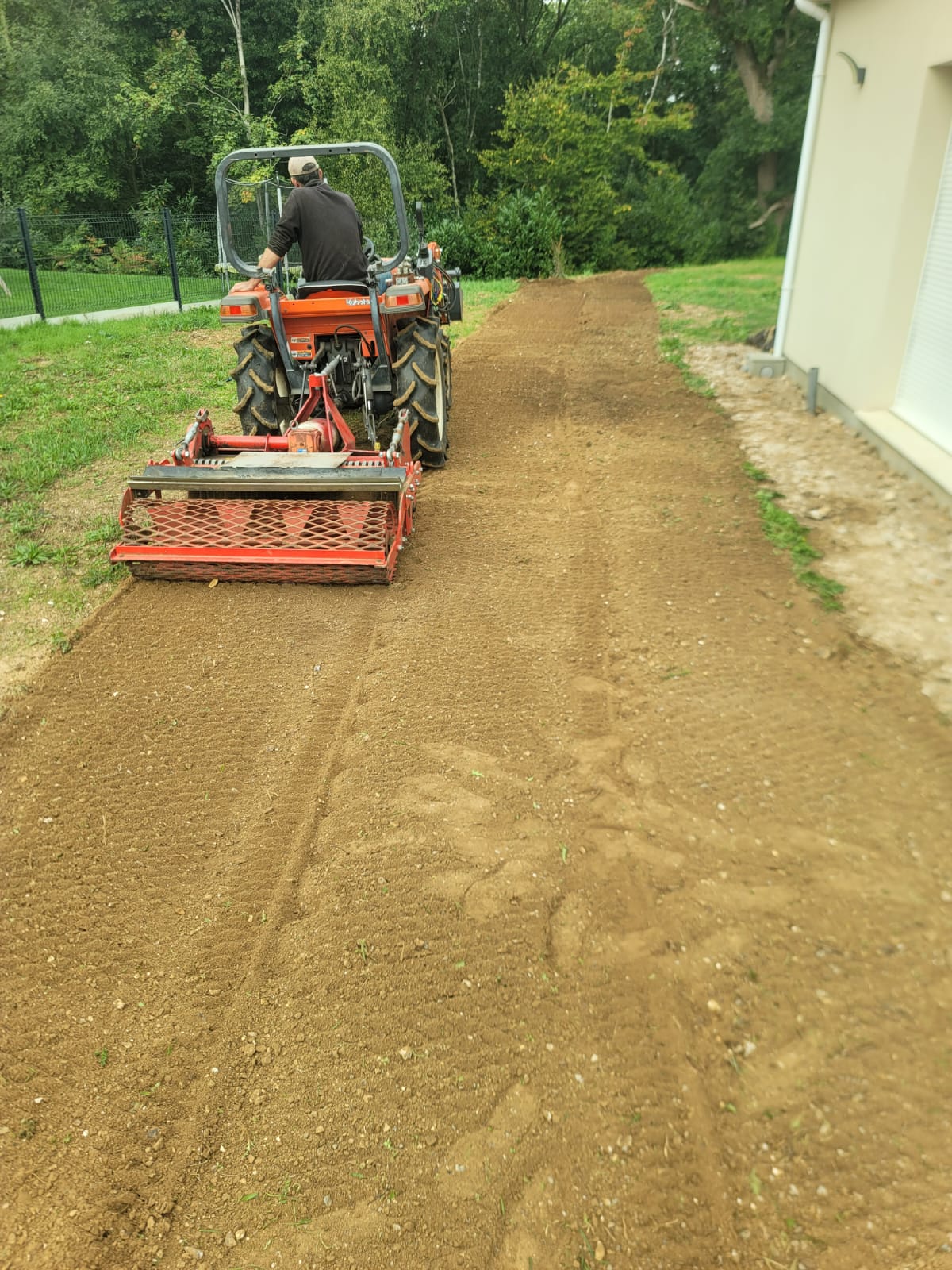 Homme conduisant un tracteur pour labourer le sol pres d une maison